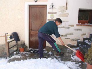 Claudio spala la neve davanti all'ingresso dell'agriturismo