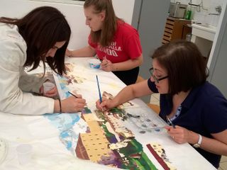 Alunne del Bertoni all'opera nel disegnare Saluzzo sull'abito da sposa