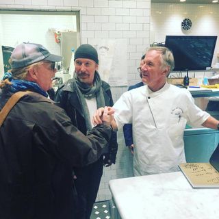 Stretta di mano tra gli chef Batali e Garola, sotto gli occhi di un divertito The Edge