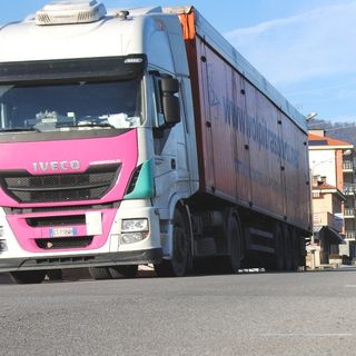 Un pesante autoarticolato carico di bottiglie d'acqua minerale transita sul Ponte Po di Paesana