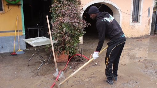 Un immigrato aiuta durante l'alluvione del 2016