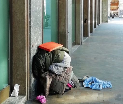 Un cumulo di coperte e stracci davanti all'ingresso del palazzo della Provincia a Cuneo