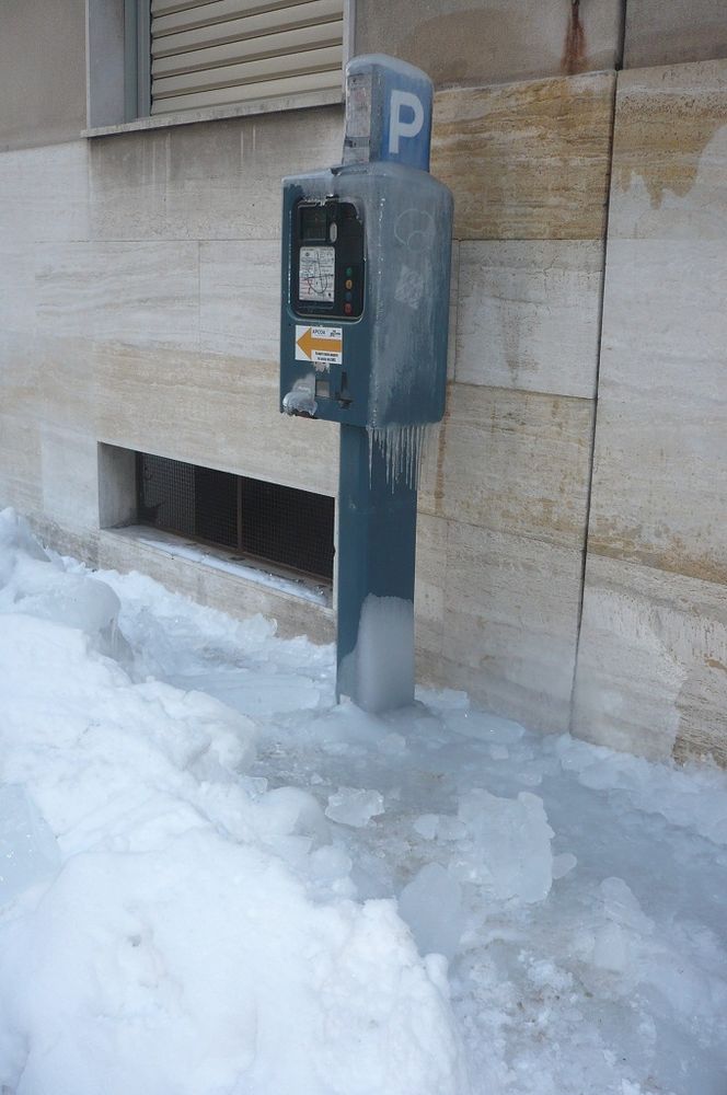 Il parcometro completamento avvolto nel ghiaccio e, nelle altre foto, la situazione intorno al distributore