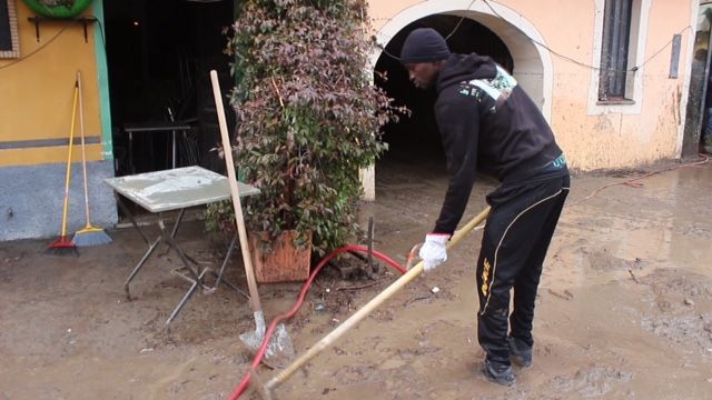 Un immigrato aiuta durante l'alluvione del 2016