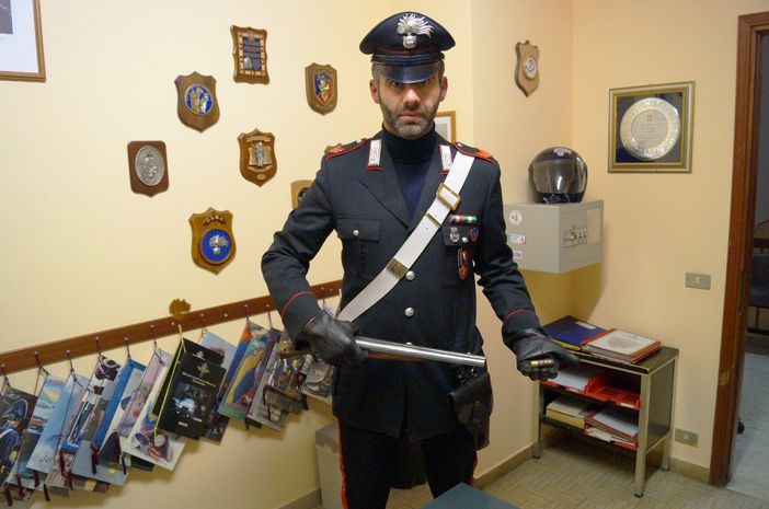 Un carabiniere mostra il fucile a canne mozze con il quale l'uomo ha sparato all'ex moglie