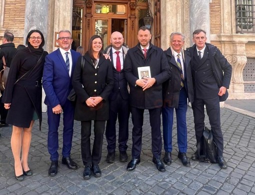 Nicola Cotti con il libro su Chiaffredo Bergia assieme al collega Stefano De Carolis, gli amministratori comunali di Paesana e i familiari, a Roma davanti al Palazzo Madama